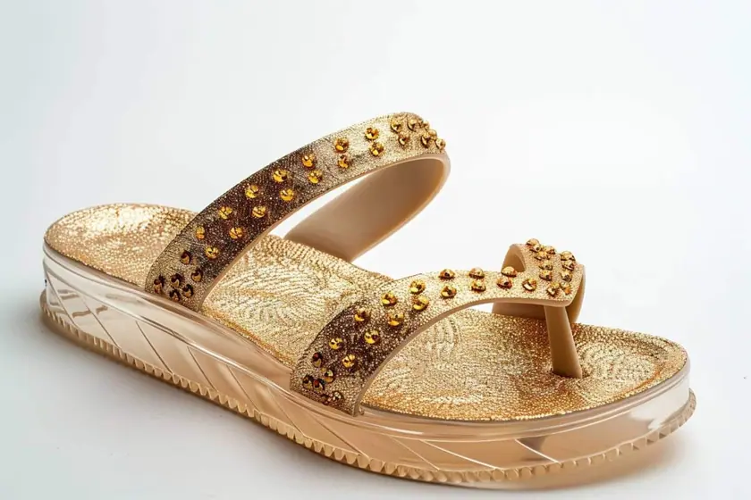 Sandales à fines brides dorées et talon fin posées sur un parquet clair