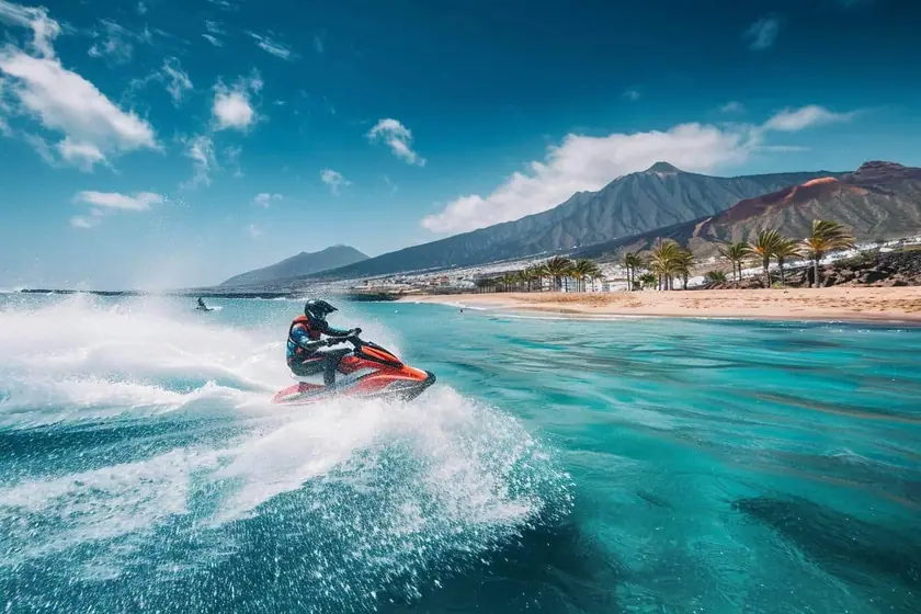 Jet ski fendant une mer calme le long d'une côte volcanique sombre baignée de soleil